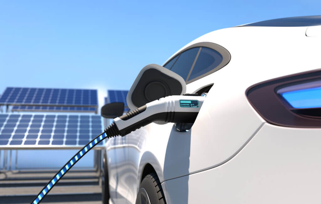 carro elétrico carregando e painéis solares atrás para representar carro movido a energia solar
