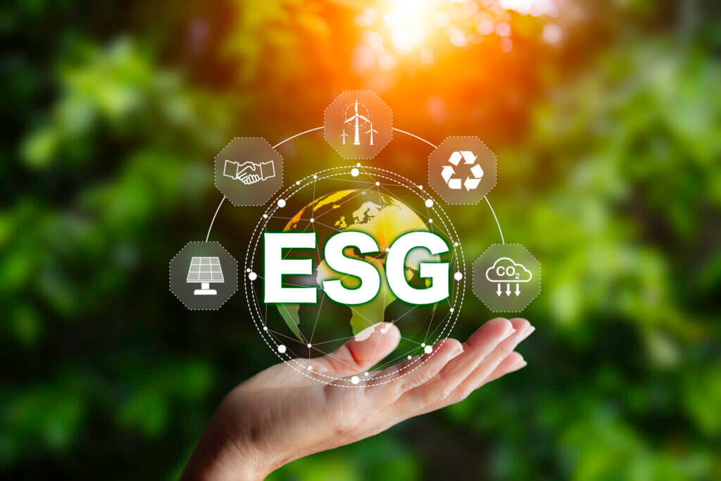 fundo desfocado com árvores e em destaque uma mão estendida mostrando ESG como se fosse um holograma