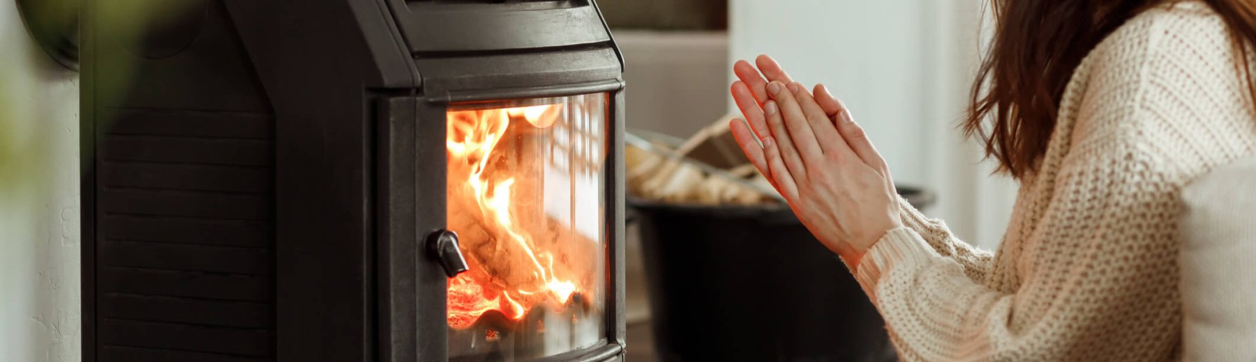 mulher aquecendo a mão em aquecedor elétrico